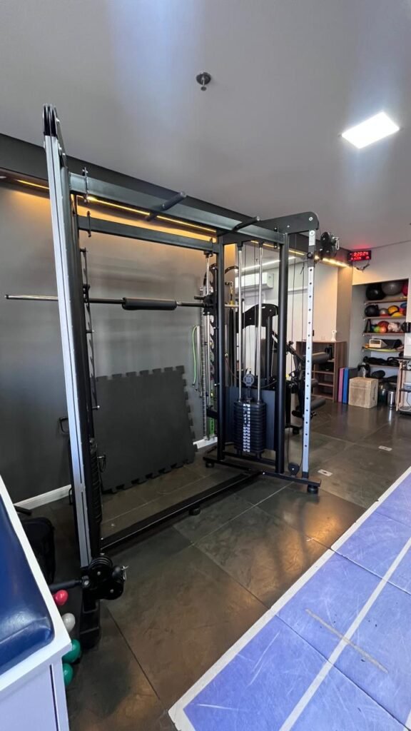 Espaço de fisioterapia funcional e reabilitação na DDC Clinic unidade São Caetano do Sul, com aparelho crossover de musculação e piso emborrachado com pista azul.
